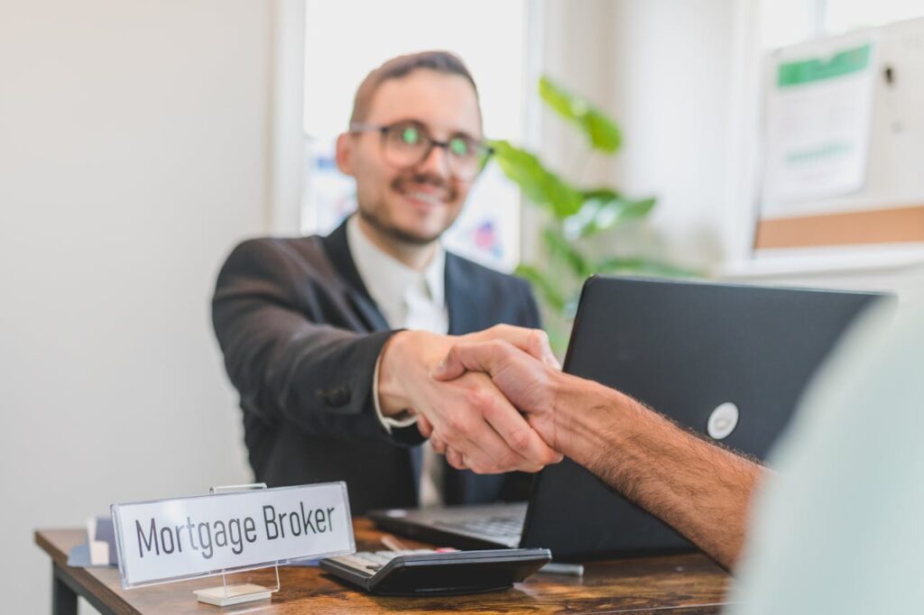pexels-photo-8293768 Mortgage broker and client sealing a deal with a handshake in a bright, modern office.